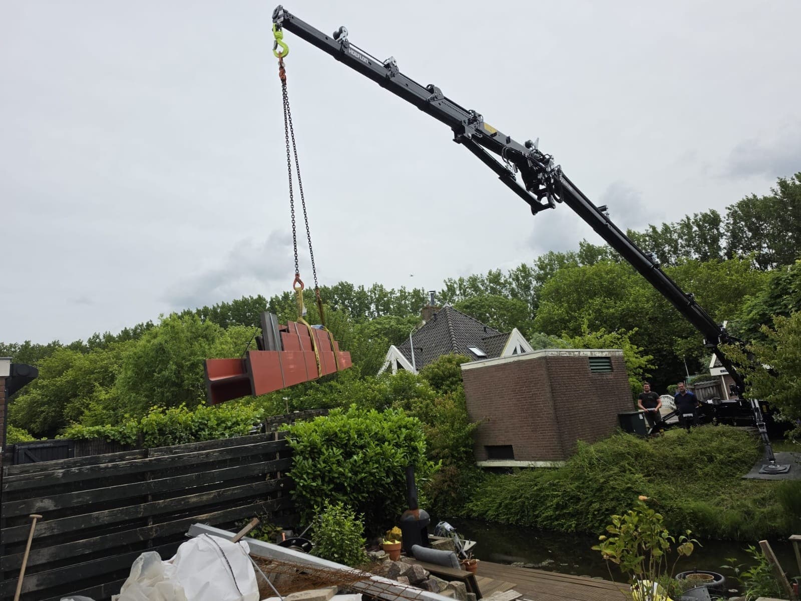Een gemenied stalen portaal gaat over tuin en water naar de achtergevel.